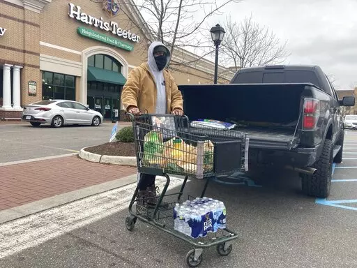 Chris Stokes picks up extra provisions at a grocery store in Norfolk, Va., on Friday Jan. 21, 2022, as the city prepares for an upcoming snowstorm.   (AP Photo/Ben Finley)