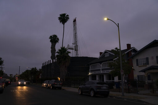 A vehicle drives past the Jefferson oil drill site located in the residential area in Los Angeles, Wednesday, June 2, 2021. University of Southern California researchers found people living near wells in Jefferson Park reported significantly higher rates of wheezing, eye and nose irritation, sore throat and dizziness than neighbors living farther away. The researchers likened the respiratory harm caused by living near the oil fields to daily exposure to secondhand smoke or exhaust from a busy hi