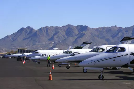 A Scottsdale Airport staffer waits on a private jet, as the airport gears up for the expected dramactic increase in private jet traffic, leading up to the NFL Super Bowl LVII football game at Scottsdale Airport in Scottsdale, Ariz., Thursday, Feb. 2, 2023. (AP Photo/Ross D. Franklin)