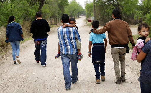 FILE - A group of migrant families walk from the Rio Grande, the river separating the U.S. and Mexico in Texas, near McAllen, Texas, March 14, 2019. A Biden administration effort to reunite children and parents who were separated under President Donald Trump's zero-tolerance border policy has made increasing progress as it nears the end of its first year. The Department of Homeland Security planned Thursday, Dec. 23, to announce that 100 children, mostly from Central America, are back with their