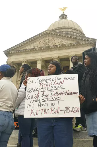 A protestor carries a sign that listed top legislative officials and their phone numbers, so Jackson residents might call and voice their opposition to Mississippi House Bill 1020, Tuesday, Jan. 31, 2023, at the Mississippi Capitol. The proposal would create a separate court system in the Capitol Complex Improvement District in Jackson. (AP Photo/Rogelio V. Solis)