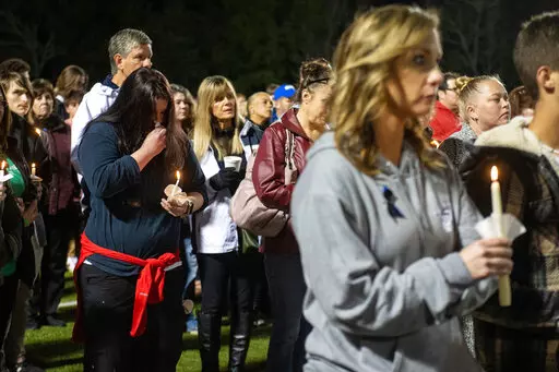 Members of the Bay St. Louis, Miss., community stand with candles during a vigil for Bay St. Louis police Sgt. Steven Robin and Officer Branden Estorffe at Tiger Stadium on Thursday, Dec. 15, 2022. Robin and Estorffe were killed the day before when a woman shot both of them. (Hannah Ruhoff/The Sun Herald via AP)