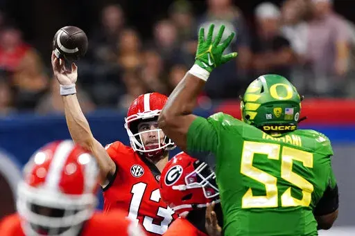 Georgia quarterback Stetson Bennett (13) throws under pressure from Oregon defensive lineman Taki Taimani (55) in the first half of an NCAA college football game Saturday, Sept. 3, 2022, in Atlanta. (AP Photo/John Bazemore)
