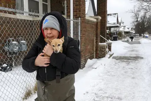 Lisa Muscat carries her dog Zoey to safety after a water main break in Detroit caused massive flooding, triggering evacuations, Monday, Feb. 17, 2025. (Andy Morrison/Detroit News via AP)