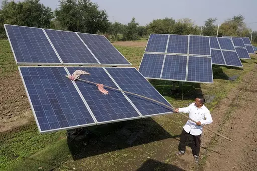 Farmer Pravinbhai Parmar cleans a solar panel installed at a farm in Dhundi village of Kheda district in western Indian Gujarat state, India, Friday, Jan. 13, 2023. The Indian government will not consider any proposals for new coal plants for the next five years and focus on growing its renewables sector, according to an updated national electricity plan released Wednesday evening. (AP Photo/Ajit Solanki, File)
