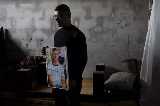 Yousef Mesheh, 15, holds a portrait of his brother, Wael in the bedroom where they were sleeping when Israeli forces stormed into their home at 3.a.m., in the Balata Refugee Camp in the northern West Bank, Tuesday, Jan. 10, 2023. They were both arrested, but Wael is still imprisoned. A report to be released next Monday by Israeli human rights organization HaMoked found that the Israeli military arrested and interrogated hundreds of Palestinian teenagers in 2022 in the occupied West Bank, without