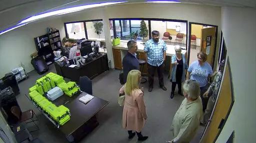 This Jan. 7, 2021, image taken from Coffee County, Ga., security video, appears to show Cathy Latham (center, long turquoise top), introducing members of a computer forensic team to local election officials. Latham was the county Republican Party chair at the time. The computer forensics team was at the county elections office in Douglas, Ga., to make copies of voting equipment in an effort that documents show was arranged by attorney Sidney Powell and others allied with then-President Donald Tr