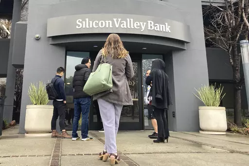 People stand outside a Silicon Valley Bank branch in Santa Clara, Calif., Friday, March 10, 2023. The Federal Reserve is scheduled Friday to release a highly-anticipated review of its supervision of Silicon Valley Bank, the go-to bank for venture capital firms and technology start-ups that failed spectacularly in March. (AP Photo/Jeff Chiu, File)
