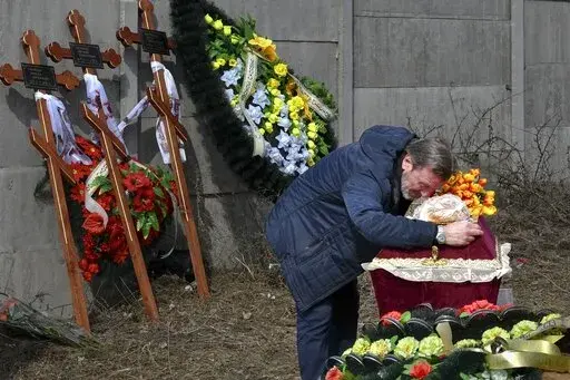 A relative mourns on the coffin with the body of 3 year-old Mykola Goryainiv, who died with his parents as they were driving a car trying to evacuate from a fighting zone in Kharkiv region, during a funeral ceremony in Kramatorsk, Ukraine, Wednesday, March 30, 2022. (AP Photo/Andriy Andriyenko)