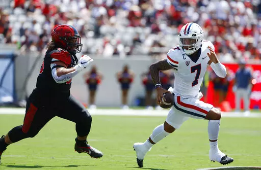 Arizona's Jayden de Laura, right, runs the ball as San Diego State's Jonah Tavai, left, defends in the second quarter of an NCAA college football game Saturday, Sept. 3, 2022, in San Diego. (K.C. Alfred/The San Diego Union-Tribune via AP)