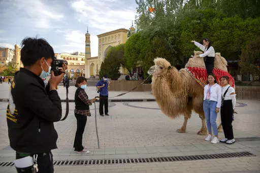 Tourists pose for photos with a camel outside the Id Kah Mosque in Kashgar in western China's Xinjiang Uyghur Autonomous Region, as seen during a government organized trip for foreign journalists, on April 19, 2021. After a U.N. report concluding that China's crackdown in the far west Xinjiang region may constitute crimes against humanity, China used a well-worn tactic to deflect criticism: blame a Western conspiracy. (AP Photo/Mark Schiefelbein, File)