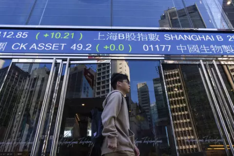 A pedestrian passes by the Hong Kong Stock Exchange electronic screen in Hong Kong, on Wednesday, March 1, 2023. Asian shares were mixed Wednesday as investors watched for upcoming earnings reports and other indicators on how inflationary pressures might be denting global growth. (AP Photo/Louise Delmotte)