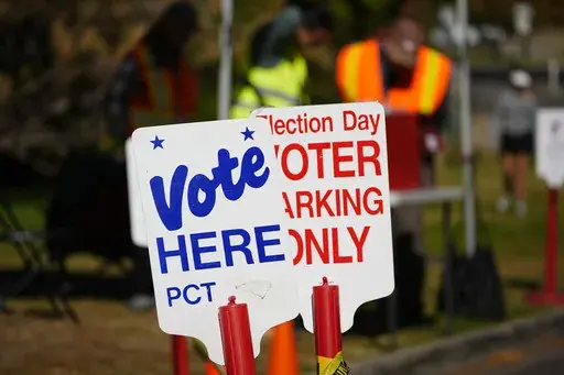Signs direct voters to a ballot drop-off location Friday, Oct. 25, 2024, in Washington Park in Denver. (AP Photo/David Zalubowski)