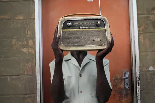 Ngwiza Khumbulani Moyo, a vintage collector holds an old radio set outside his home in Bulawayo, Wednesday, Feb. 15, 2023. According to a survey by Afrobarometer, radio is "overwhelmingly" the most common source of news in Africa. About 68% of respondents said they tune in at least a few times a week, compared to about 40% who said they use social media and the internet. (AP Photo/Tsvangirayi Mukwazhi)