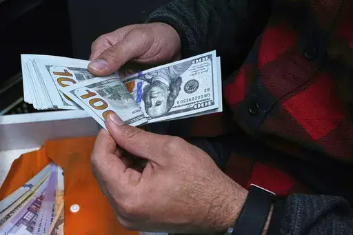 A currency exchange bureau worker counts U.S. dollars at Ferdowsi square, Tehran's go-to venue for foreign currency exchange, in downtown Tehran, Iran, Saturday, April 5, 2025. (AP Photo/Vahid Salemi)