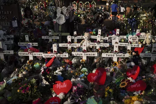Flowers are piled around crosses with the names of the victims killed in a school shooting as people visit a memorial at Robb Elementary School to pay their respects May 31, 2022, in Uvalde, Texas. Families in Uvalde, Texas, are digging in for a new test of legal protections for the gun industry as they mark one year since the Robb Elementary School shooting. Both the U.S. government and gun manufacturers in recent years have reached large settlements following some of the nation's worst mass sh