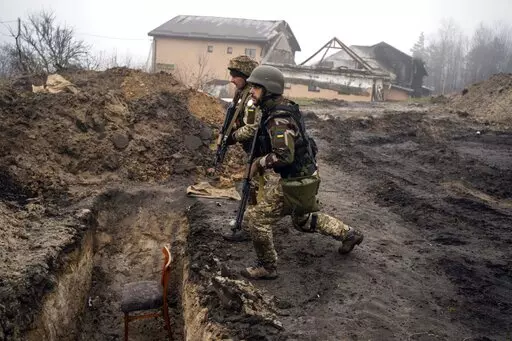 Ukrainian soldiers approach a trench that had been used by Russian soldiers as they retake an area on the outskirts of Kyiv, Ukraine, Friday, April 1, 2022. (AP Photo/Rodrigo Abd)
