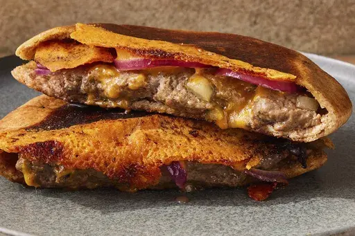 This image released by Milk Street shows a recipe for pita burgers with crisped cheese. (Milk Street via AP)