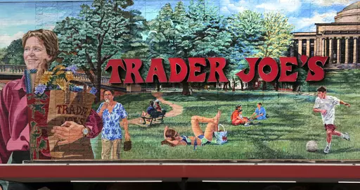 The Trader Joe's logo hangs on a mural, Aug. 13, 2019, in Cambridge, Mass. Trader Joe's recently upped the price to 23 cents for a single banana, marking a 4-cent increase from the grocer's previous going rate for the fruit that remained unchanged for over 20 years. (AP Photo/Charles Krupa, File)