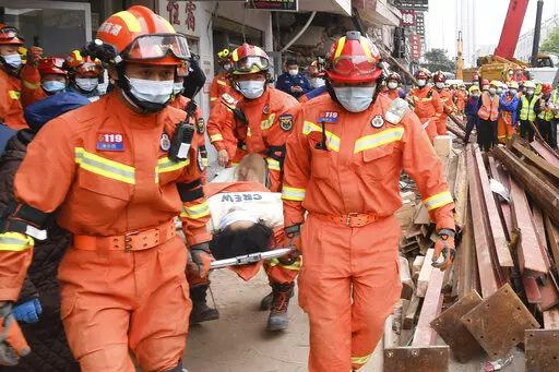 In this photo released by Xinhua News Agency, rescuers evacuate a woman pulled alive from a collapsed building in Changsha, central China's Hunan Province, May 1, 2022. The woman was rescued Sunday from the rubble of a building in central China more than 50 hours after it collapsed, leaving dozens trapped or missing, state media said. (Shen Hong/Xinhua via AP)