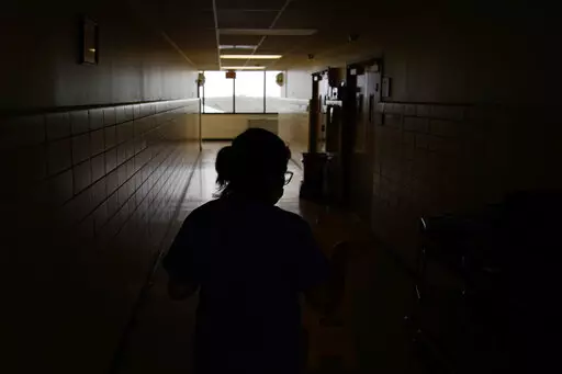 A chief nursing officer walks down a hallway in the recently reopened emergency room at a hospital  in Houma, La., on Friday, Sept. 3, 2021. Patients worried about getting smacked with an unexpected bill after emergency care gained a layer of protection in January 2022 from a new federal law. The No Surprises Act prevents doctors or hospitals in many situations from billing insured patients higher rates because the care providers are not in their insurer’s coverage network. (AP Photo/John Loch