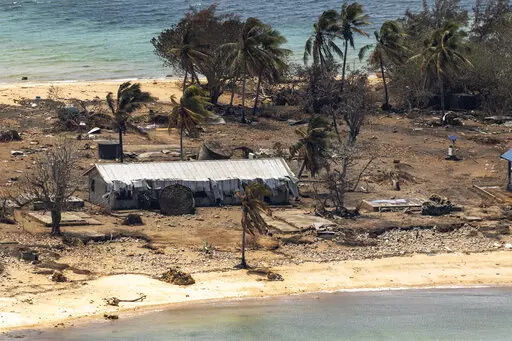 In this photo provided by the Australian Defence Force debris from damaged building and trees are strewn around on Atata Island in Tonga, Jan. 28, 2022, following the eruption of an underwater volcano and subsequent tsunami. The international aid Tonga accepted after the disaster has caused the country's first COVID-19 outbreak, and there are worries the isolation that kept Tonga and other Pacific nations virus-free until now will hurt their ability to manage the public health threat.(POIS Chris