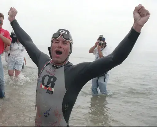 FILE- With his right eye swollen shut from the swim, Jim Dreyer emerges victorious from the water, Aug. 3, 1998, after completing a 43.2-mile, 41-hour crossing of Lake Michigan. (Jon M. Brouwer/The Grand Rapids Press via AP, File)