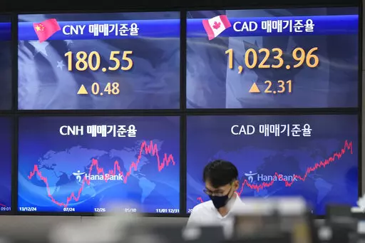 A currency trader walks near the screens showing the foreign exchange rates at a foreign exchange dealing room in Seoul, South Korea, Tuesday, Oct. 11, 2022. Asian shares were mostly lower on Tuesday as losses in technology-related shares weighed on global benchmarks.(AP Photo/Lee Jin-man)