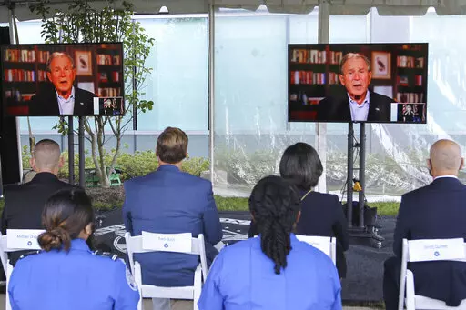 Screens display a video of former President George W. Bush speaking during an event to commemorate the 20th anniversary of the Sept. 11, 2001, terrorist attacks, Saturday, Sept. 11, 2021, in Springfield, Va. (AP Photo/Luis M. Alvarez)