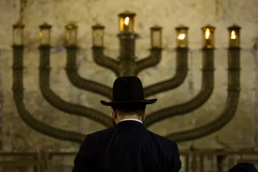 An Ultra-Orthodox Jewish man stands in front of a menorah on the third eve of Hanukkah, at the Western Wall, Judaism's holiest site in Jerusalem's old city, Sunday, Dec. 13, 2009. On eight consecutive nightfalls, Jews gather with family and friends to light one additional candle in the menorah candelabra. They do so to commemorate the rededication of the Temple in Jerusalem in the 2nd century BC, after a small group of Jewish fighters liberated it from occupying foreign forces. (AP Photo/Sebasti