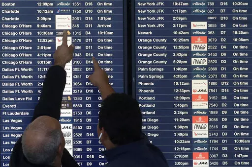 Two men point toward plane arrivals on a flight information board at San Francisco International Airport in San Francisco, Tuesday, Nov. 26, 2019.   Forecasters say, Friday, March 11, 2022,  a powerful, late-winter storm combining rivers of moisture and frigid temperatures is expected to dump snow from the Deep South all the way north to the Canadian border over the weekend that could cause travel problems and power outages across a wide part of the Eastern United States from late Friday through