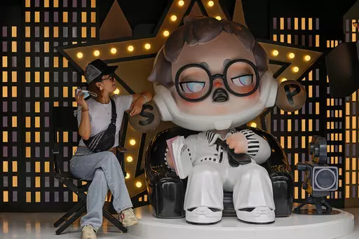 A woman holding her face mask poses with a toy figure on display at a popular shopping street in Shanghai, China, Sunday, Aug. 29, 2021. (AP Photo/Andy Wong)