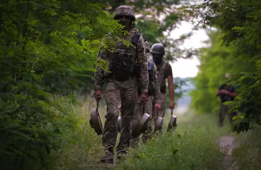 A Ukraine special operations unit carries anti-tank mines to bury on a forest track to prevent Russian troops from advancing toward their trenches, in the Donetsk region, Ukraine,Tuesday, June 14, 2022. (AP Photo/Efrem Lukatsky)