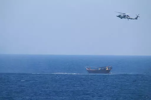 A U.S. Navy Seahawk helicopter flies over a stateless dhow later found to be carrying a hidden arms shipment in the Arabian Sea, May 6, 2021. The U.S. Navy's Mideast-based 5th Fleet will begin Tuesday, July 5, 2022, to offer rewards for information that could help sailors intercept weapons, drugs and other illicit shipments across the region. The program launches against the backdrop of tensions over Iran’s nuclear program and Tehran’s arming of Yemen’s Houthi rebels. (U.S. Navy via AP, Fi