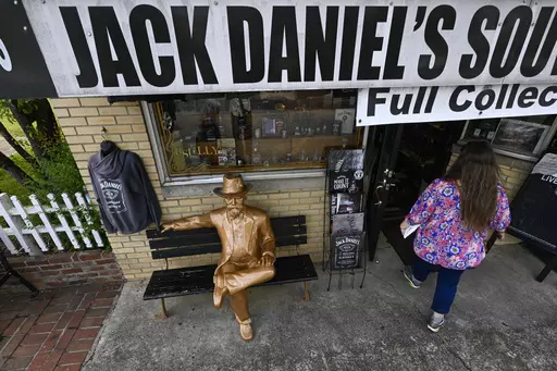 A statue of Jack Daniels sits on a bench as a visitor enters a souvenir shop in the town where the distillery is located Wednesday, June 14, 2023, in Lynchburg, Tenn. A destructive and unsightly black fungus which feeds on ethanol emitted by whiskey barrels has been found growing on property near the distillery's nearby barrelhouses which has resulted in a lawsuit against it. (AP Photo/John Amis)