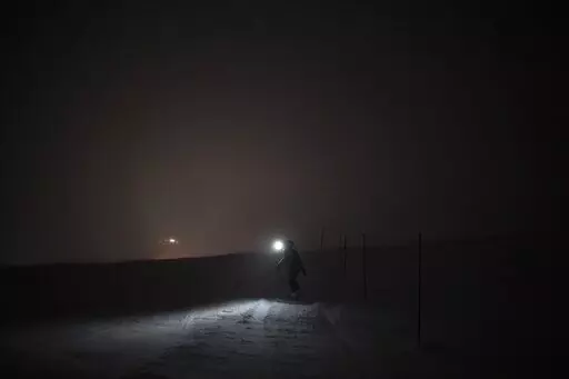 The Rev. Siv Limstrand walks with her rifle to the church's cabin in Bolterdalen, Norway, Monday, Jan. 9, 2023. For the lone pastor in this fragile, starkly beautiful environment, the challenge is to fulfill the church's historical mission of ministering to those in crisis while addressing a pressing and divisive contemporary challenge. "We pray every Sunday for everyone who's affected by climate change," Limstrand said. (AP Photo/Daniel Cole)