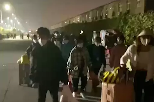In this photo taken from video footage and released by Hangpai Xingyang, people with suitcases and bags are seen leaving from a Foxconn compound in Zhengzhou in central China's Henan Province on Saturday, Oct. 29, 2022. Workers in a Foxconn facility in the central Chinese city of Zhengzhou appear to have left the facility to avoid COVID-19 curbs, with many traveling by foot days after an unknown number of factory workers were quarantined in the facility following a virus outbreak. (Hangpai Xingy