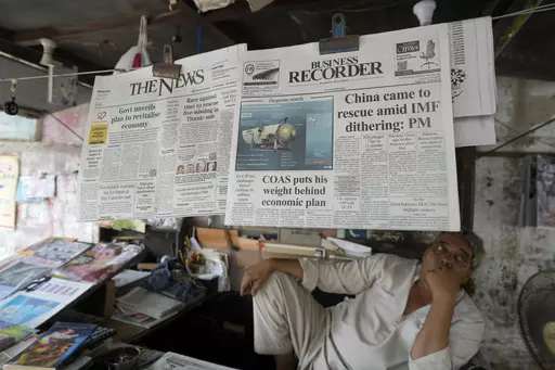 A vendor sits beside a copy of a morning newspaper which reports missing Titanic submersible and onboard five people, including Pakistani nationals Shahzada Dawood and his son Suleman, at a stall, in Karachi, Pakistan on June 21, 2023. The saga of a lost submersible that had gone into the depths of the ocean to see the Titanic wreckage rippled across the national and global conversation. But a far bigger disaster days earlier, the wrecking of a ship off Greece filled with migrants, didn't become