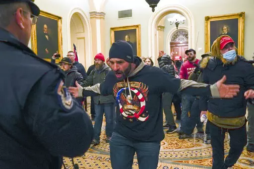 In this Jan. 6, 2021, photo, Trump supporters, including Douglas Jensen, center, confront U.S. Capitol Police in the hallway outside of the Senate chamber at the Capitol in Washington. The Iowa construction worker and QAnon follower was sentenced Friday, Dec. 16, 2022, to five years in prison for his role in the Jan. 6, 2021, insurrection at the U.S. Capitol, when he led a crowd chasing a police officer who diverted rioters away from lawmakers. (AP Photo/Manuel Balce Ceneta, File)