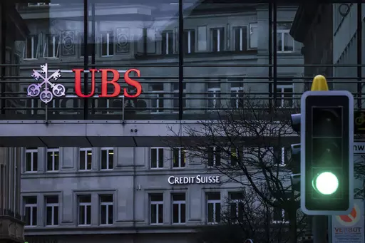 A traffic light signals green in front of the logos of the Swiss banks Credit Suisse and UBS in Zurich, Switzerland, on March 19, 2023. Analysts say the UBS takeover of embattled rival Credit Suisse has shaken Switzerland’s self-image and dented its reputation as a global financial center. They warn that the country’s prosperity could grow too dependent on a single banking behemoth. (Michael Buholzer/Keystone via AP, File)