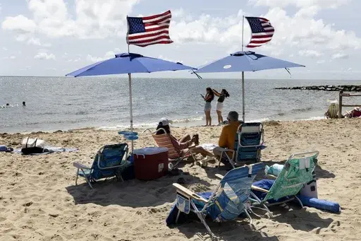 People fly the American flag on their beach umbrellas, Friday, Aug. 30, 2024, in Dennis Port, Mass. (AP Photo/Michael Dwyer)