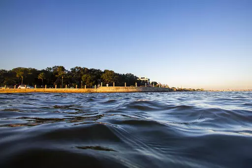 As high tide laps against the sea wall tourist walk down the Battery in Charleston, S.C. Friday, Nov. 13, 2020. According to a U.S. federal report released on Tuesday, Feb. 15, 2022, seas lapping against America’s coastlines are rising ever faster and will be 10 to 12 inches higher by the year 2050 with major U.S. Eastern cities regularly hit with costly sunny day flooding. (AP Photo/Mic Smith, File)