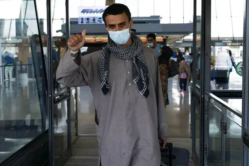 Families evacuated from Kabul, Afghanistan, walk through the terminal before boarding a bus after they arrived at Washington Dulles International Airport, in Chantilly, Va., on Friday, Aug. 27, 2021. (AP Photo/Jose Luis Magana)