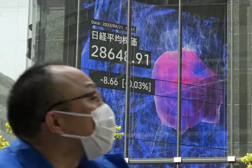 A person walks past an electronic stock board showing Japan's Nikkei 225 index at a securities firm Friday, April 21, 2023 in Tokyo. Shares are weaker in Asia after benchmarks dipped on Wall Street following mixed earnings reports from big companies and more signals the U.S. economy may be slowing. (AP Photo/Shuji Kajiyama)
