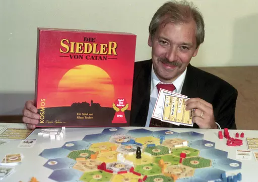 Klaus Teuber, a dental technician from Darmstadt, presents his game "The Settlers of Catan", Friday, Sept. 29, 1995, in Frankfurt, Germany. Teuber, creator of the hugely popular Catan board game in which players compete to build settlements on a fictional island, passed away on April 1, 2023 after a short and serious illness, according to a family statement. He was 70. (AP Photo/Bernd Kammerer, File)