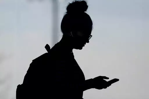 A woman checks her phone in Orem, Utah, on Nov. 14, 2019. A survey of people ages 16 to 40 finds that millennials and Generation Z follow the news, but they aren't that happy with what they're seeing. The study conducted by The Associated Press-NORC Center for Public Affairs Research and the American Press Institute says 79% of people follow news daily, contrary to perceptions that many are tuned out. (AP Photo/Rick Bowmer, File)
