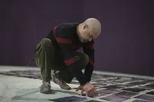 French street artist Shuck One tears up archive images as he prepares a mural for the exhibition "Paris Noir", at the Centre Pompidou Museum, in Paris, Tuesday, Feb. 18, 2025. (AP Photo/Thibault Camus)
