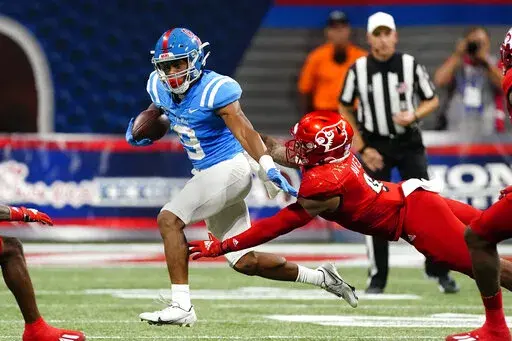 Mississippi running back Jerrion Ealy (9) tries to escape from Louisville linebacker C.J. Avery (9) during the first half of an NCAA college football game Monday, Sept. 6, 2021, in Atlanta. (AP Photo/John Bazemore)