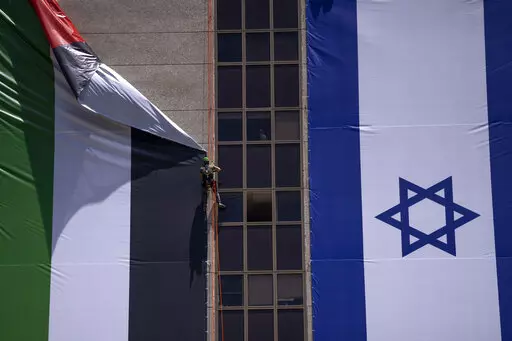 A Palestinian flag is removed from a building by Israeli authorities after being put up by an advocacy group that promotes coexistence between Palestinians and Israelis, in Ramat Gan, Israel, Wednesday, June 1, 2022. In recent weeks, Israeli authorities have gone out of their way to challenge the hoisting of the Palestinian flag. Palestinian citizens of Israel see the campaign against the flag as another affront to their national identity and their rights as a minority in the majority Jewish sta