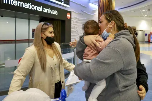 Families embrace after a flight from Los Angeles arrived at Auckland International Airport as New Zealand's border opened for visa-waiver countries Monday, May 2, 2022. New Zealand welcomed tourists from the U.S., Canada, Britain, Japan and more than 50 other countries for the first time in more than two years as it dropped most of its remaining pandemic border restrictions. (Jed Bradley/New Zealand Herald via AP)